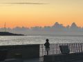 Una niña observa el atardecer en litoral coruñés, desde la Coraza
