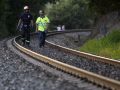 Un tren de mercancías descarrila en As Neves y deja un herido Dos miembros de equipos de emergencia caminan por las vías del tren