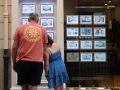 Dos personas observan los precios de viviendas en una inmobiliaria