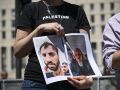 Un manifestante muestra las fotografías de los dos activistas de la flotilla que permanecen detenidos en Israel, durante una protesta este sábado