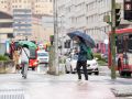 Varios viandantes tratas de protegerse de la lluvia, en Os Mallos