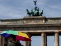 Una persona se refugia del calor con un paraguas frente a la puerta del Brandemburgo de Berlín
