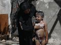 Una mujer palestina lava a su hijo entre las ruinas de una vivienda en Gaza