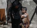 Una mujer palestina lava a su hijo entre las ruinas de una vivienda en Gaza