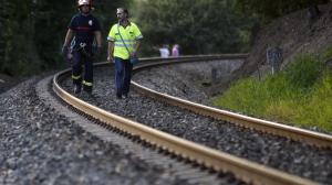 Dos miembros de equipos de emergencia caminan por las vías del tren