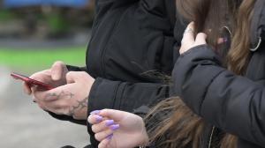 Una persona, con el móvil, en un banco de la ciudad