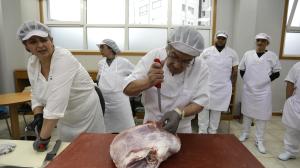 Un alumno manipula, este miércoles, una pieza de carne ante la supervisión de su profesora 