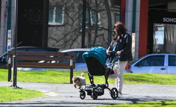 Una mujer pasea un bebé en la plaza del Balneario de Arteixo