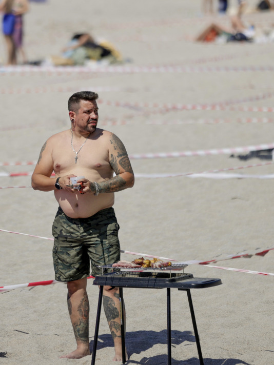 Un hombre prepara una churruscada en la playa de Riazor @Cabalar