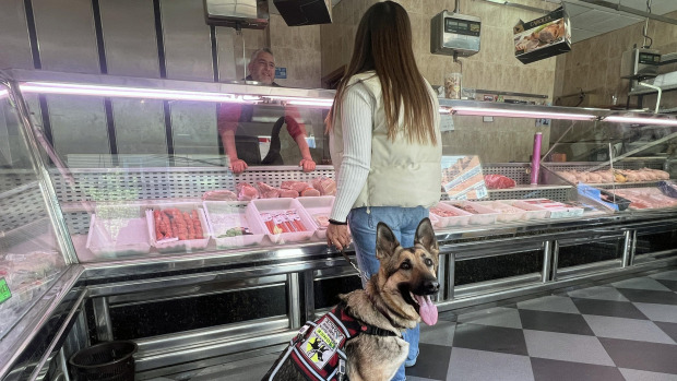 Una usuaria de la ONCE con un perro guía en una carnicería