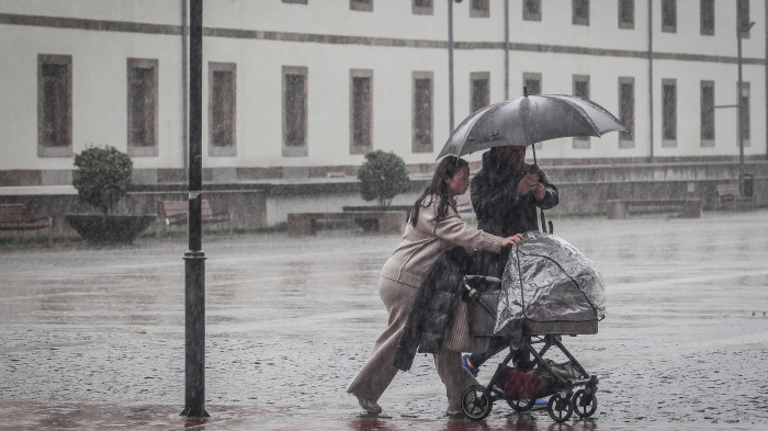 Una pareja trata de protegerse de la lluvia durante esta racha de lluvia prolongada