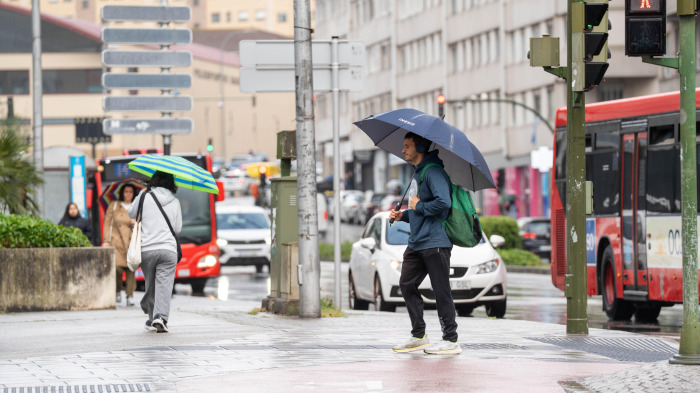 Varios viandantes tratas de protegerse de la lluvia, en Os Mallos