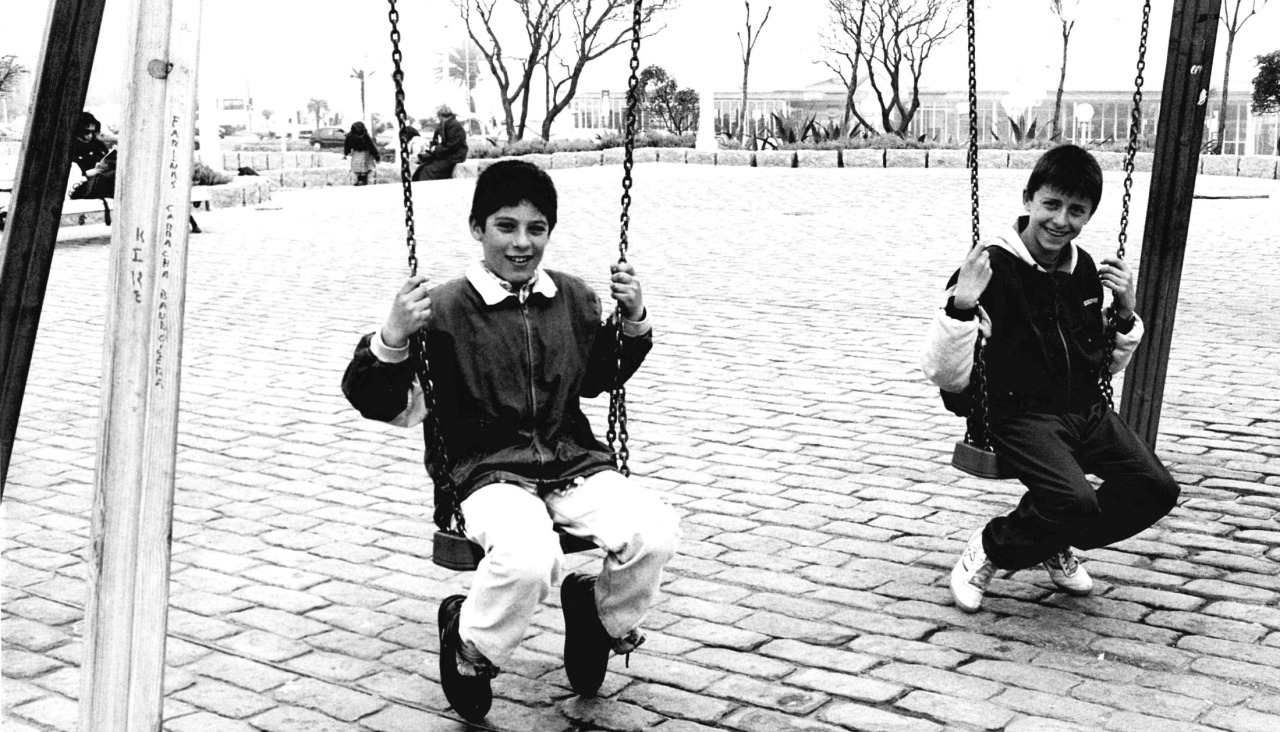 Dos niños juegan en los columpios de la plaza de Portugal