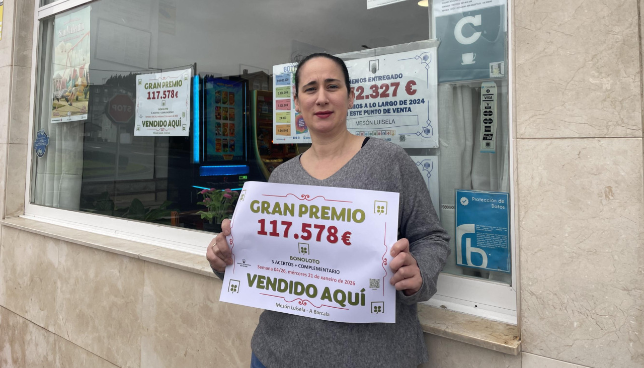 Geni Lado, propietaria del Luisela, posa con el cartel del premio en la Bonoloto