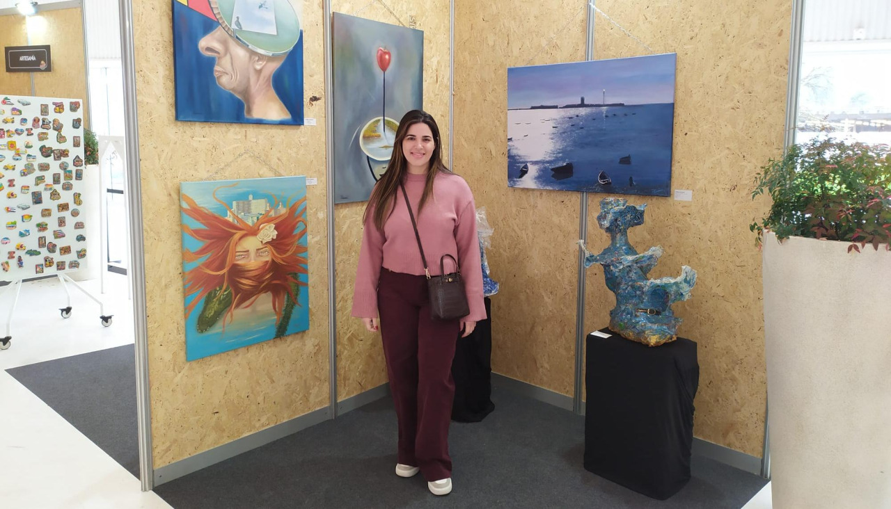 Iliana Ugando posa junto a sus cuadros en ExpoCoruña