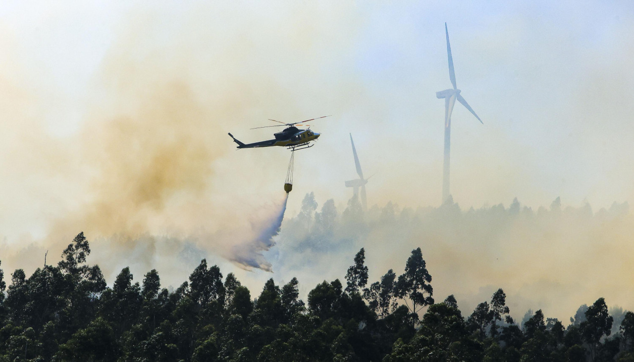 Un helicóptero descarga agua sobre un incendio forestal en la localidad coruñesa de Padrón el 13 de junio