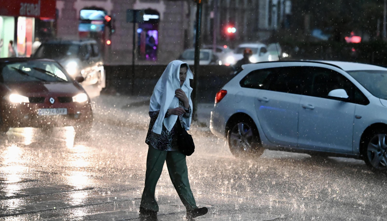 Una mujer trata de protegerse de la lluvia, la última jornada mojada del verano