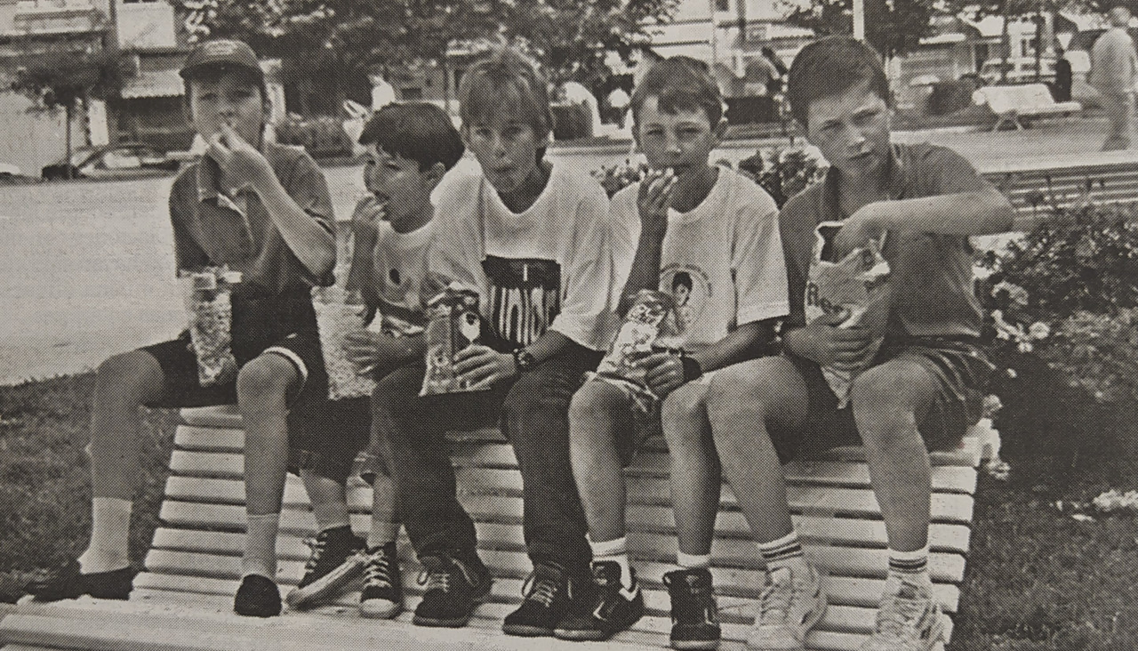 Niu00f1os comen aperitivos en un banco de A Coruu00f1a