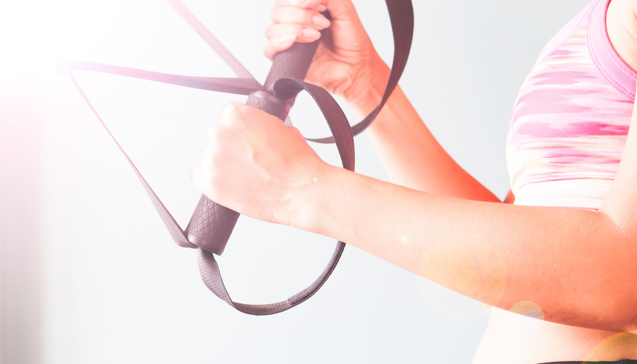 Fitness femenina en sujetador de deporte rosa con las manos en trx copiar el espacio