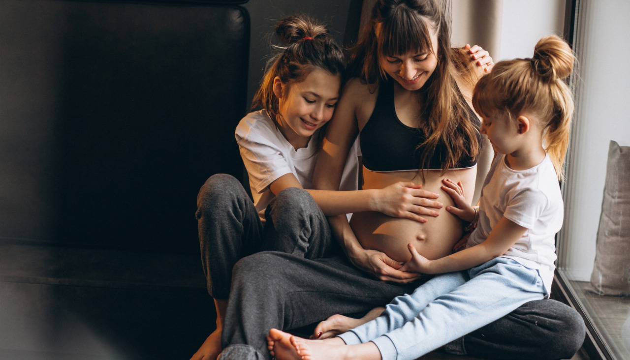 Mujer embarazada con ninos sentados junto la ventana