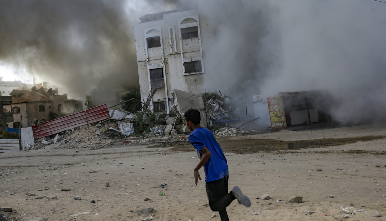 Un joven corre a resguardarse durante un ataque israelí en ciudad de Gaza