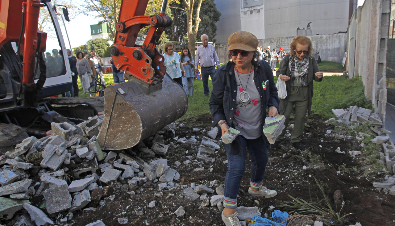 Flor Antelo y Chus Piñeiro, dos vecinas, recolectan piedras del muro