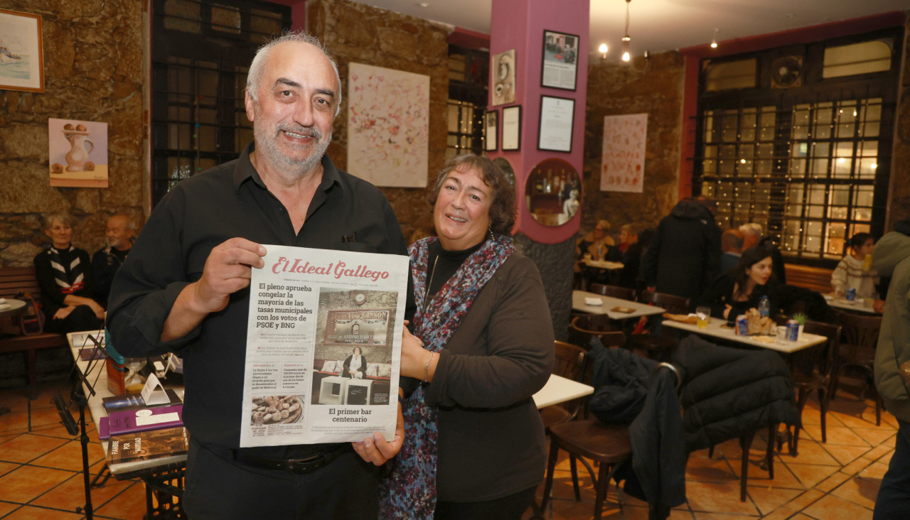 Un cliente posa junto a la propietaria con la portada de El Ideal