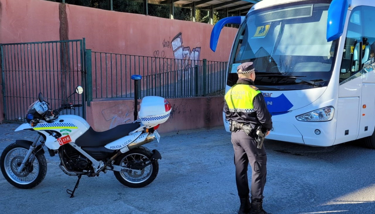 Un policía local realiza unha inspección nun autobús de transporte escolar