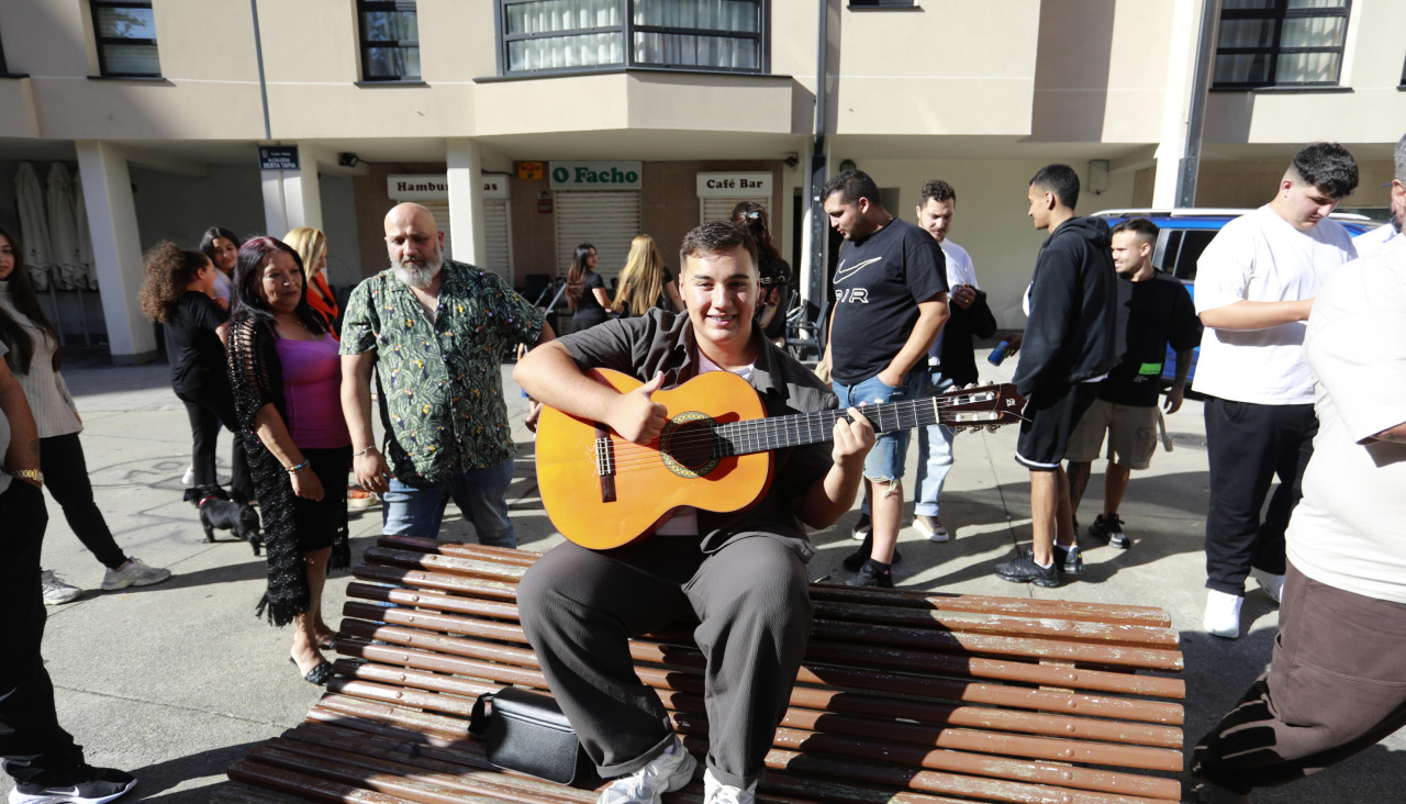 Emilio, con una guitarra, rodeado ayer de su familia en la plaza de la alcaldesa Berta Tapia, en Labañou