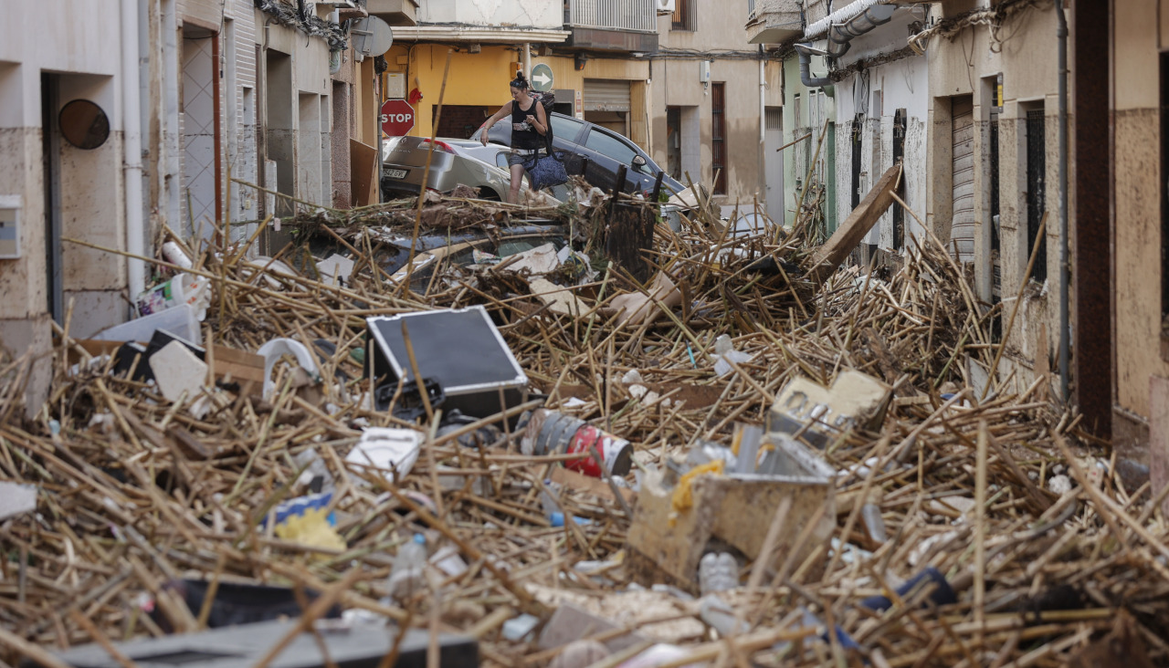 Una mujer camina entre los escombros acumulados de una calle de Paiporta