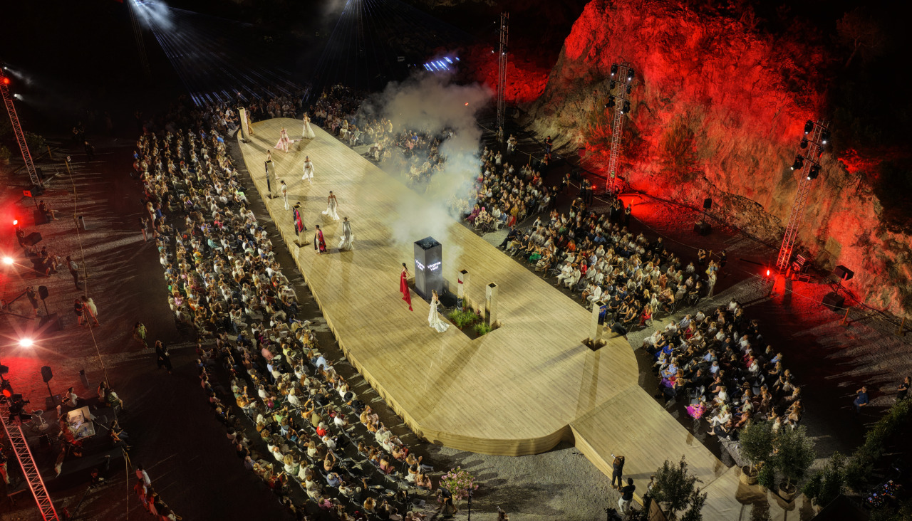 Vista aérea de otro desfile de moda, con la pasarela integrada en un entorno natural y gran afluencia de público