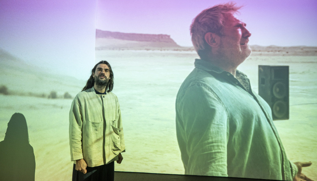 El director de ‘Sirat’, el gallego Oliver Laxe, durante un acto con un fotograma de la película de fondo