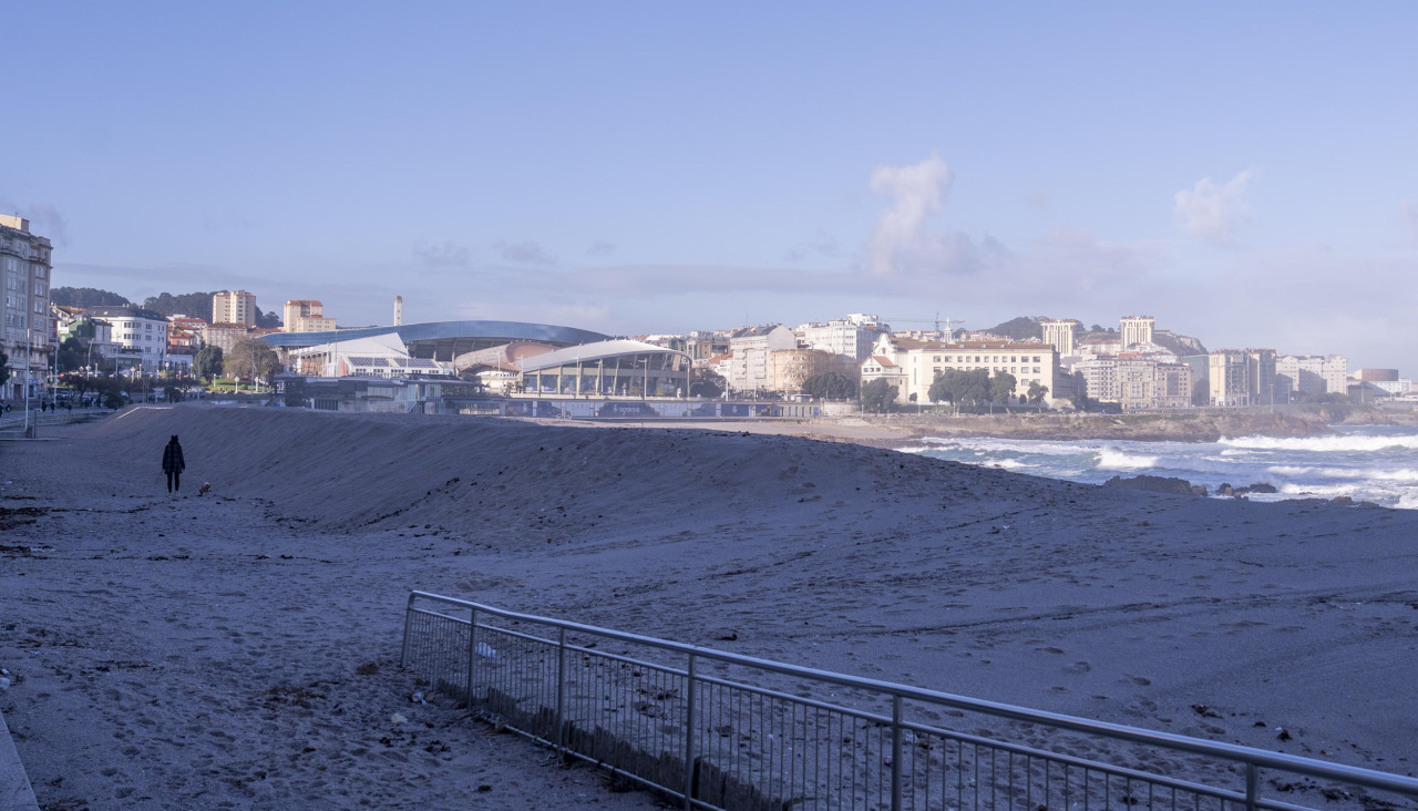 Una persona pasea por la playa de Riazor protegida por la duna