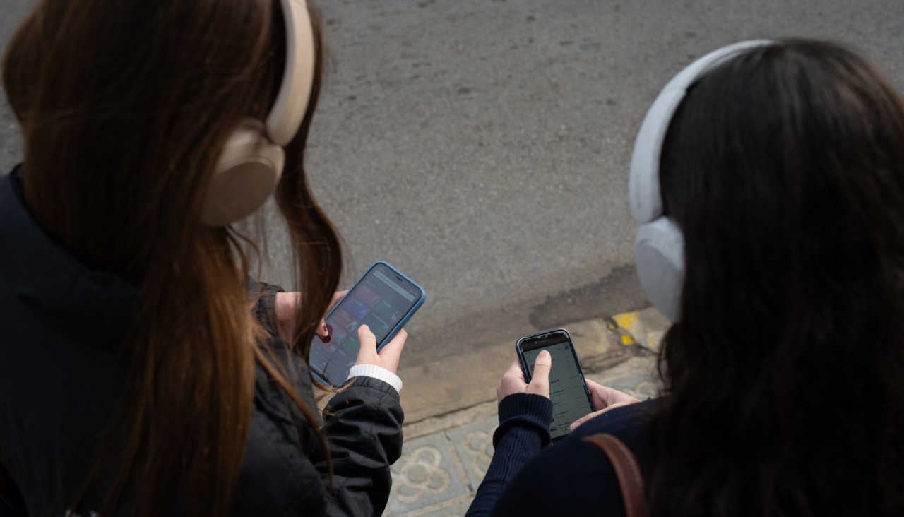 Dúas mozas consultan os seus teléfonos móbiles