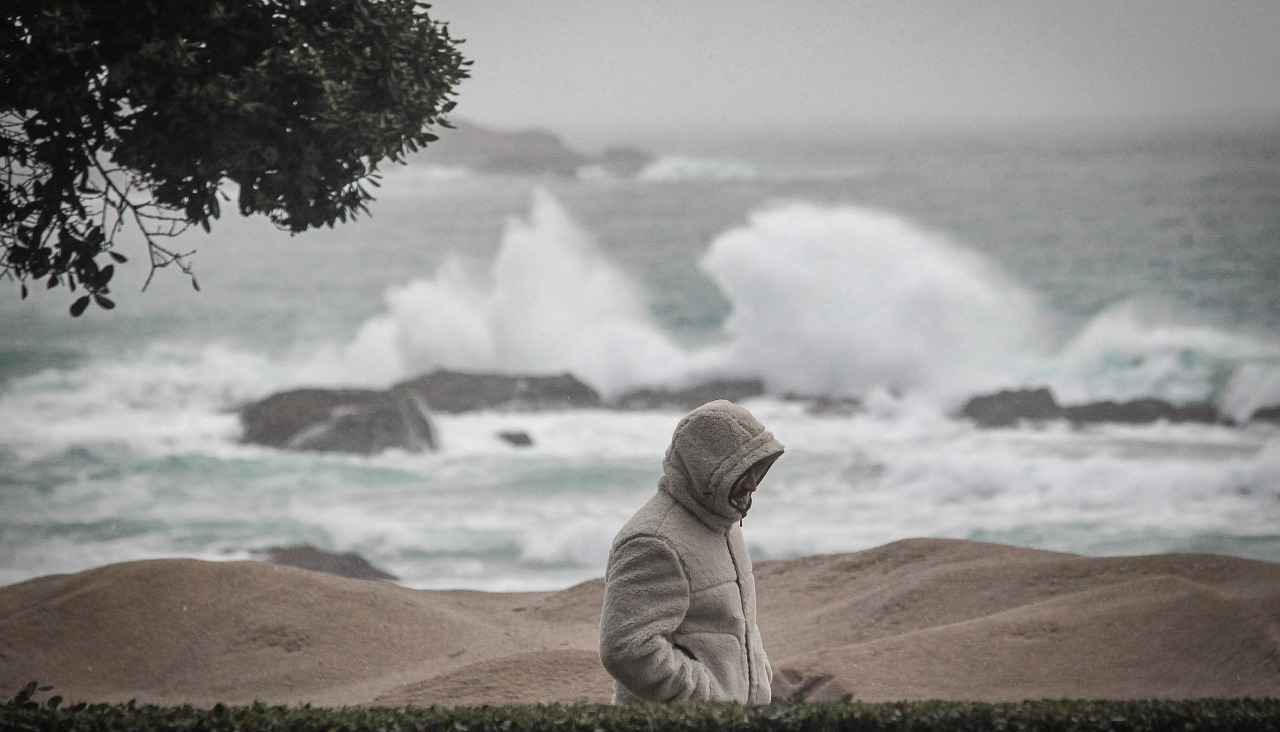 Un hombre camina sobre el Paseo Marítimo, ayer, en plena alerta naranja en el mar por oleaje
