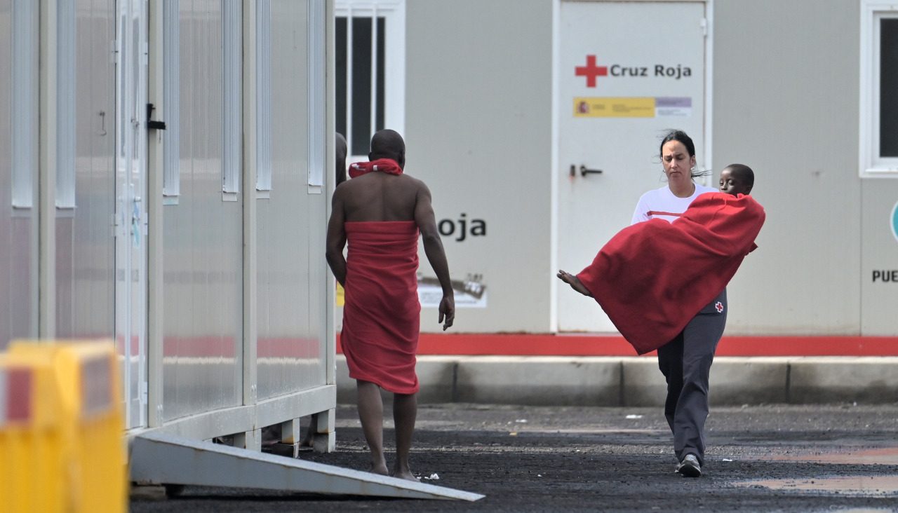 Una trabajadora de Cruz Roja lleva en brazos a un menor migrante en la isla canaria de El Hierro 