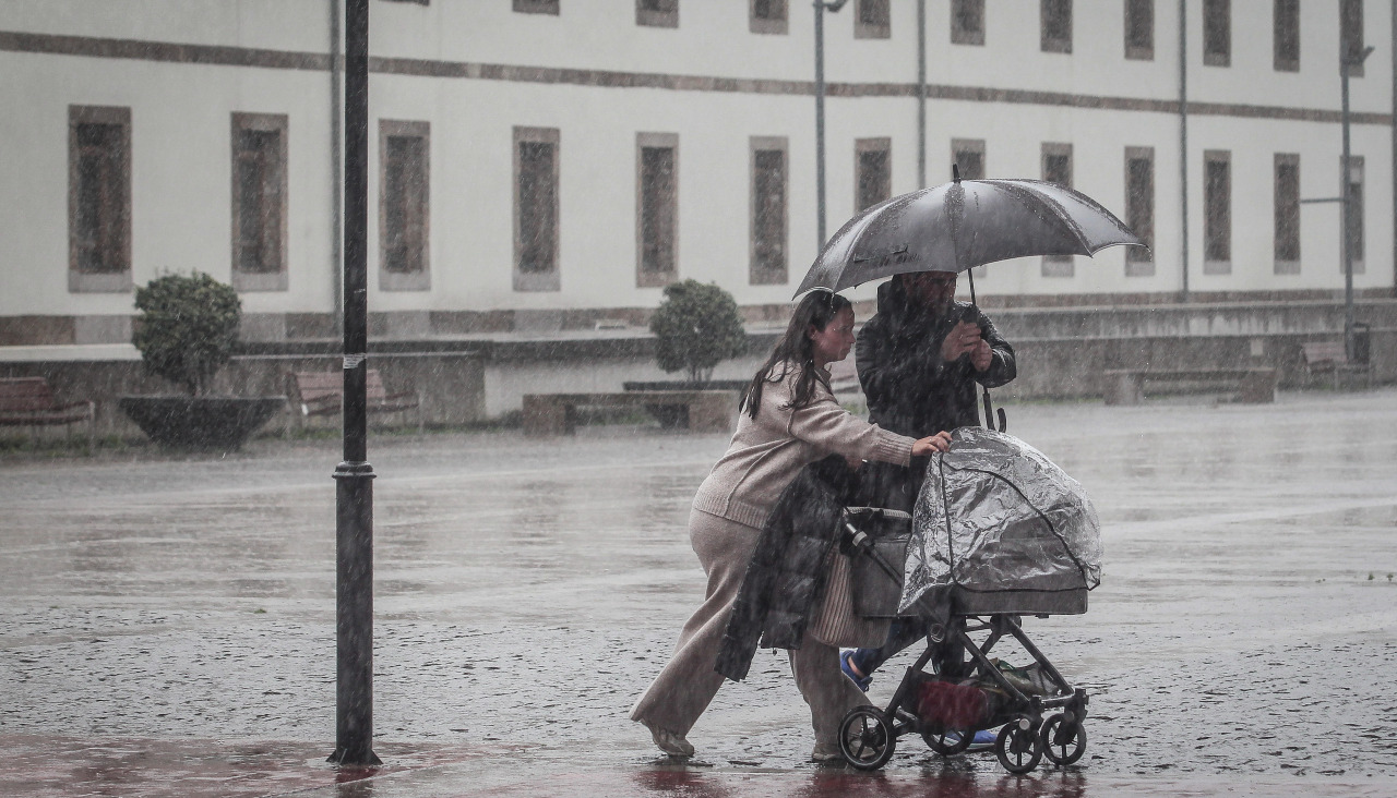Una pareja trata de protegerse de la lluvia durante esta racha de lluvia prolongada