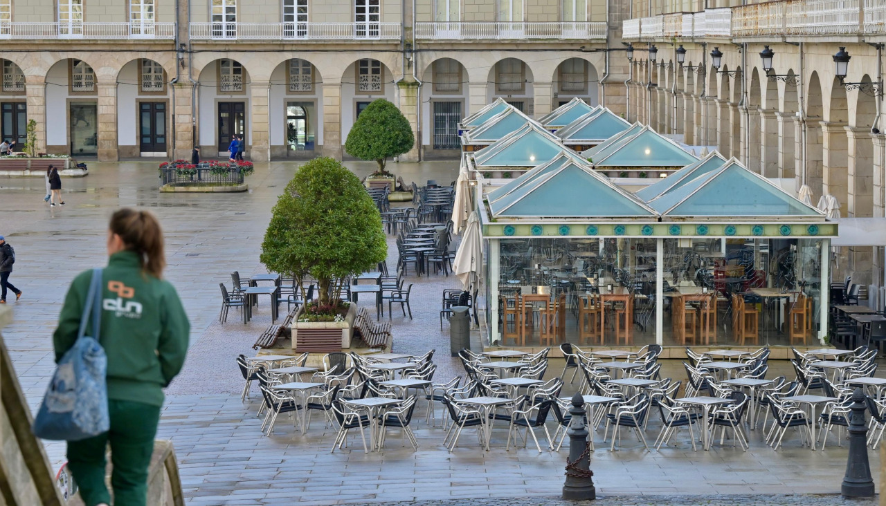 Una persona se dirige a la plaza de María Pita, con las terrazas al fondo