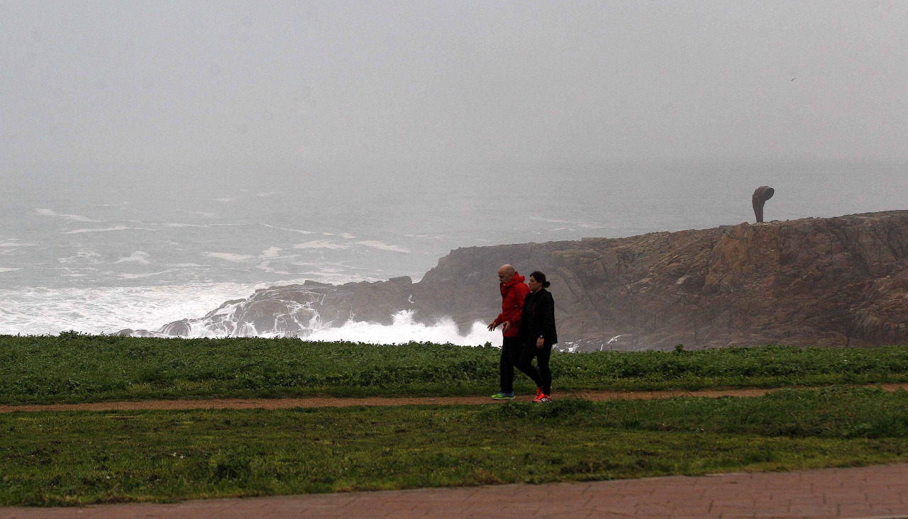 Dos paseantes caminan junto al mar