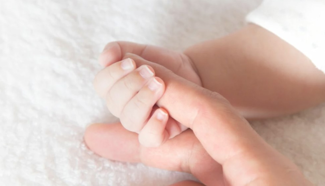 Un bebé sujeta el dedo de su madre