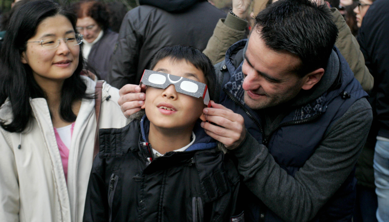Un hombre coloca las gafas protectoras a un niño, durante un eclipse parcial en A Coruña 