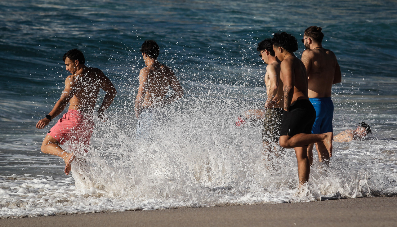 Varios jóvenes disfrutan de las altas temperaturas, esta tarde, en la playa del Orzán