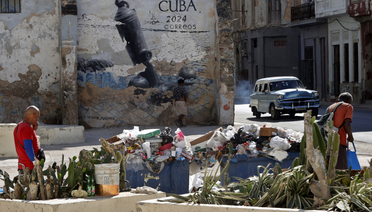 AME7437. LA HABANA (CUBA), 25/03/2026.- Personas caminan frente a residuos de basura este miércoles, en una cale de la Habana (Cuba). EFE/ Ernesto Mastrascusa
