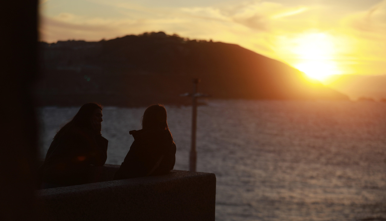 Dos personas observan una puesta de sol desde la plaza de la Domus