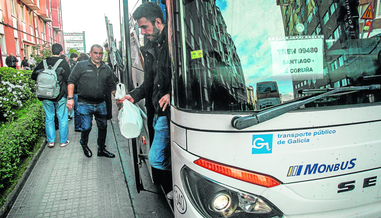 Viajeros se bajan del transporte alternativo de Renfe, durante el último corte en la estación de tren de A Coruña