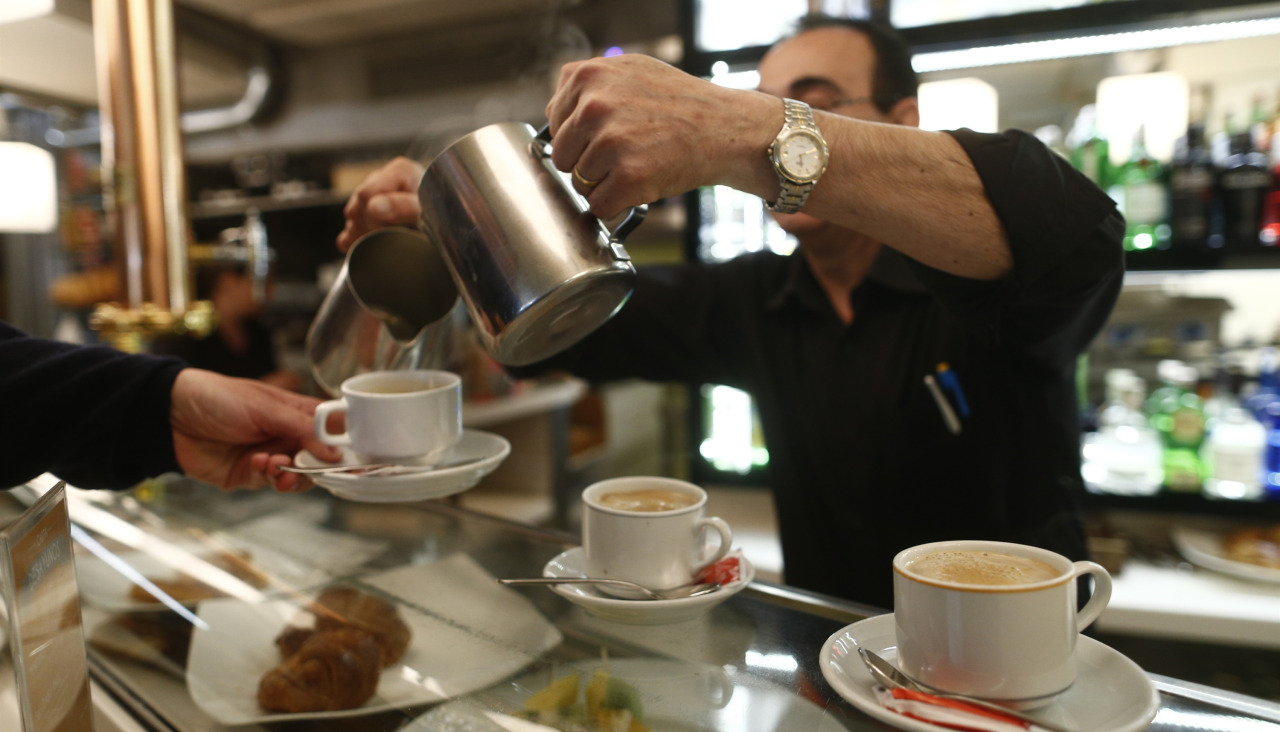 Un camarero sirve un café con leche en un local de hostelería
