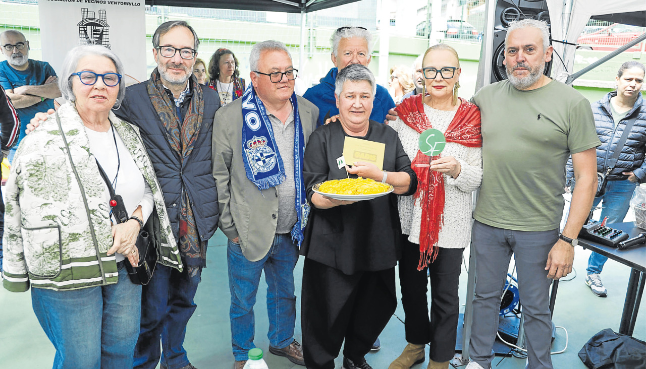 El jurado y la directiva de la asociación vecinal de la Sagrada Familia posan con la ganadora y su tortilla | germán barreiros