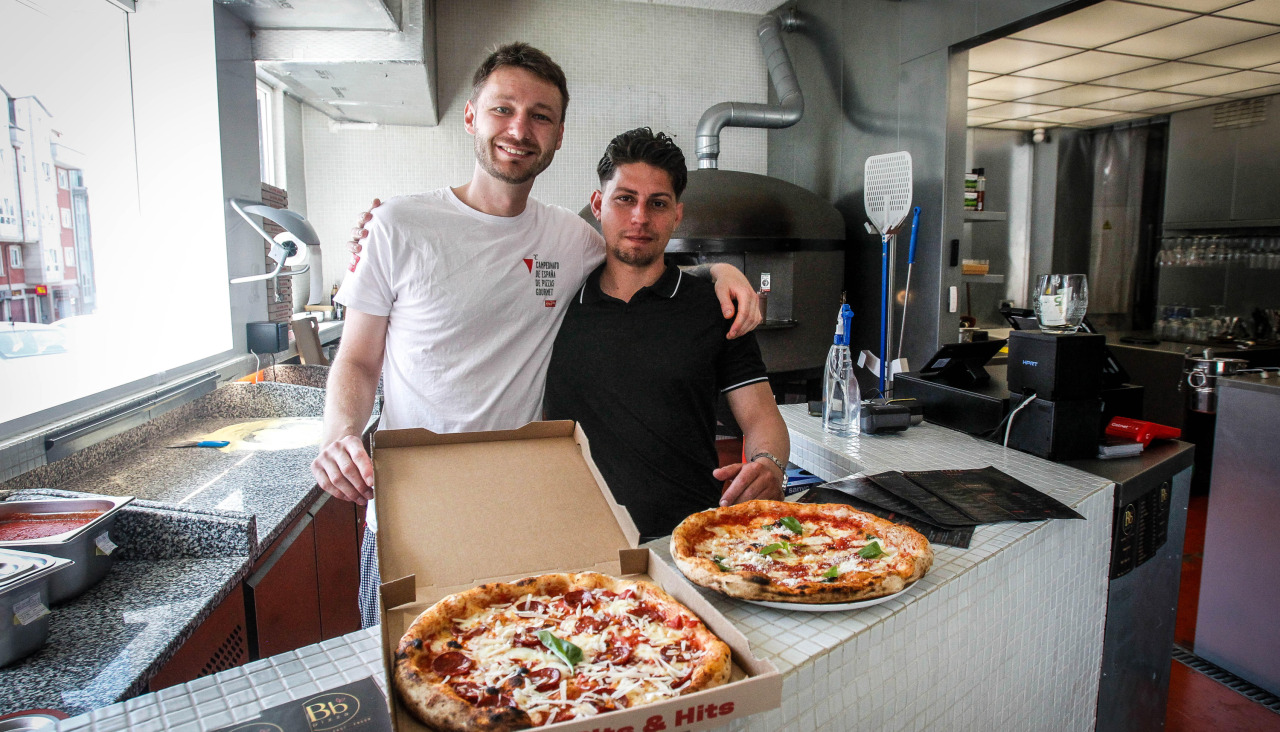 Yehor Hatchenko y Giomy Sierra posan con sus pizzas en O TemplePizzería bb pizza, en O Burgo
