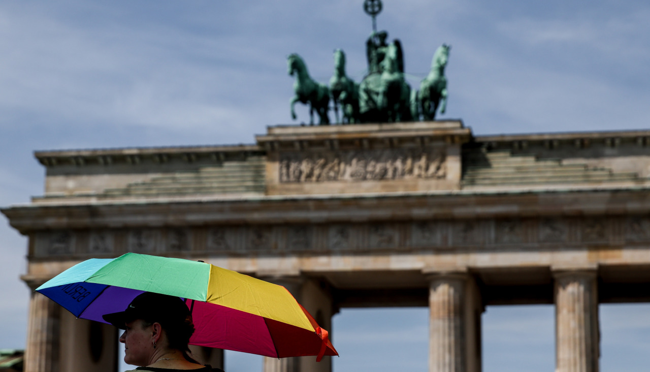 Una persona se refugia del calor con un paraguas frente a la puerta del Brandemburgo de Berlín