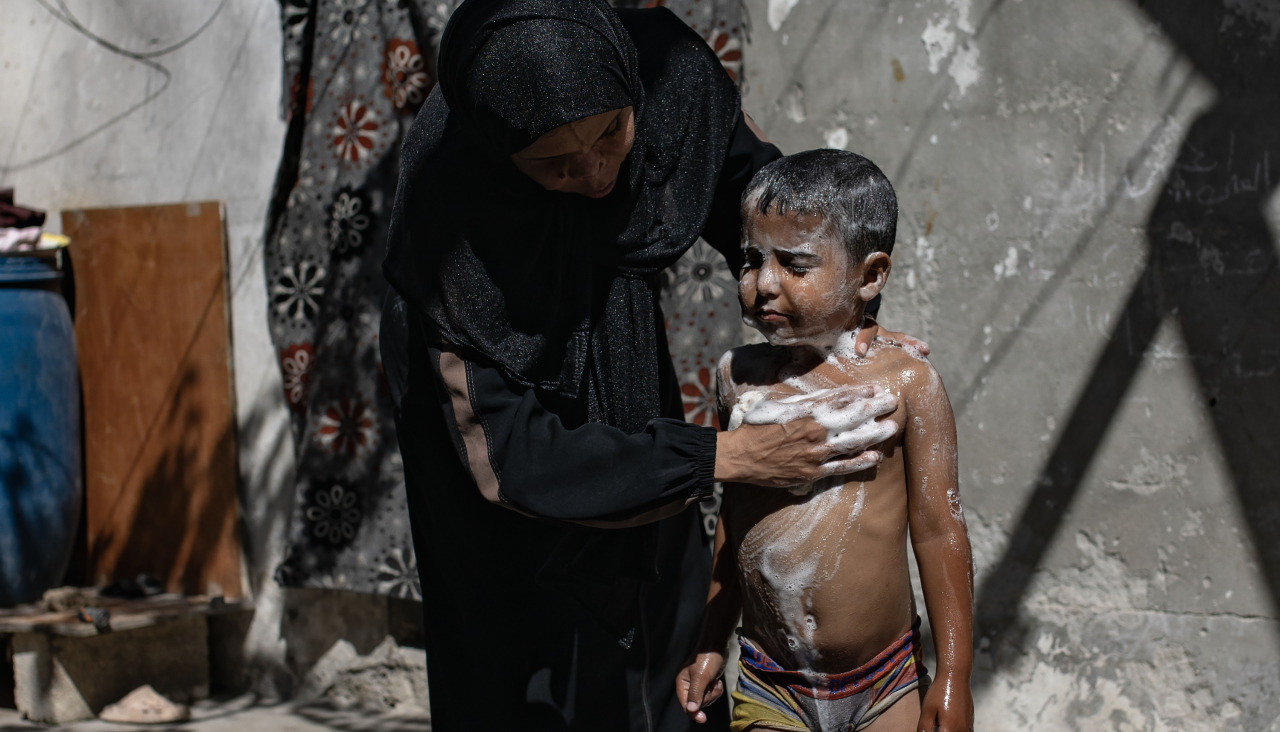 Una mujer palestina lava a su hijo entre las ruinas de una vivienda en Gaza